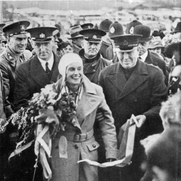 [Jean Batten surrounded by officials and supporters at the conclusion of her England - New Zealand flight]